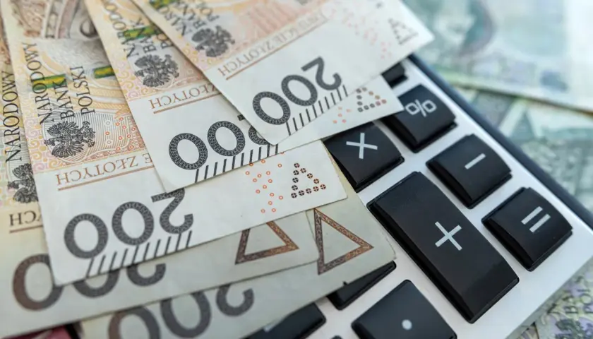 Polskie banknoty 200 zł leżą na kalkulatorze. Obliczanie pcc.