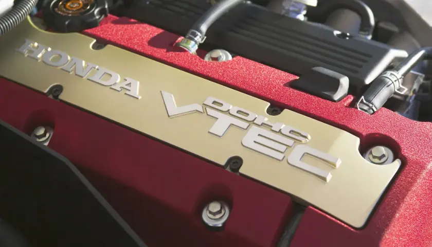 Złota pokrywa silnika Honda z napisem VTEC. To technologia, która zapewnia moc i oszczędność.