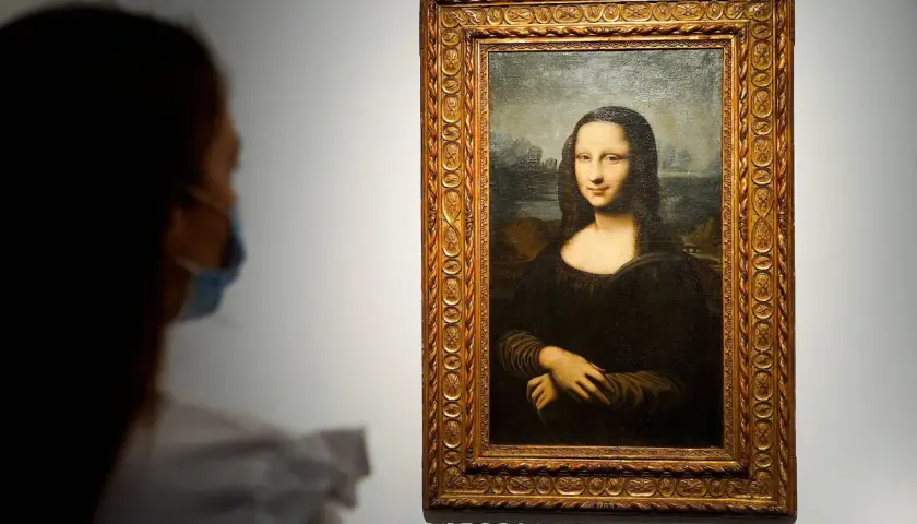 Eine Person mit Maske betrachtet die Mona Lisa. Ihre rätselhafte Bedeutung fasziniert seit Jahrhunderten.