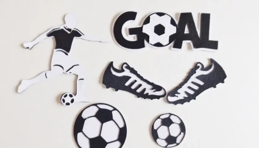 Silueta de futbolista pateando balón, dos botas, tres balones y la palabra "GOAL" en manualidades de fútbol.