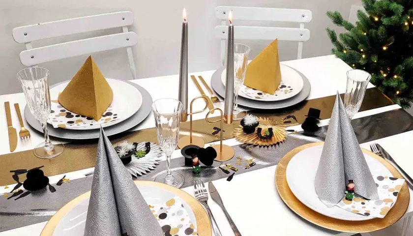 Festlich gedeckter Tisch mit Kerzen, Gläsern und Servietten in Gold und Silber. Eine tolle Silvester Idee für eine glamouröse Feier.
