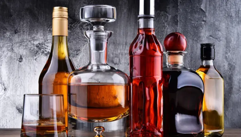 Karafka z koniakiem i inne butelki z brandy na drewnianym blacie.