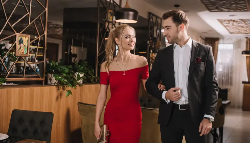 Para elegancko ubrana para, ona w czerwonej sukni, on w garniturze, idzie na wieczorne wyjście w stylu cocktail attire.