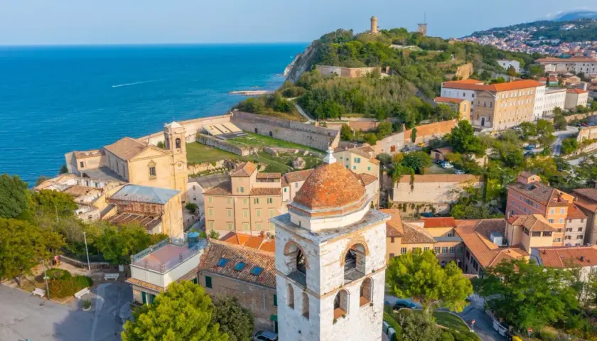 Panoramica aerea di Ancona, Marche, con il mare blu, edifici storici, un campanile e la fortezza sul colle.