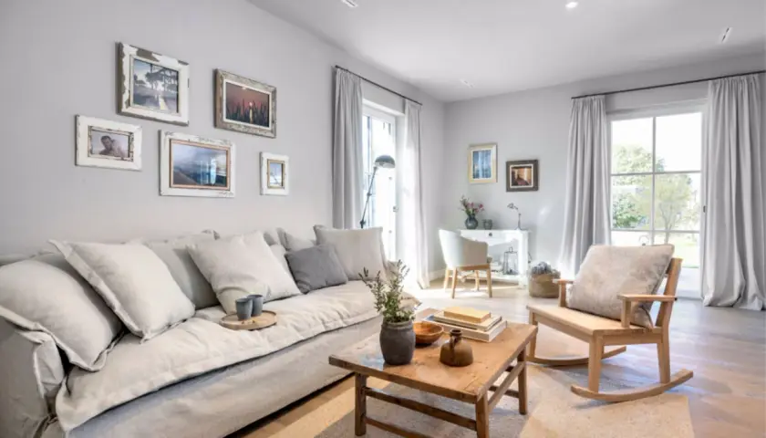Gemütliches Wohnzimmer mit einem großen grauen Sofa, Bilderwand und Schaukelstuhl. Tolle wohnzimmer ideen graues sofa.