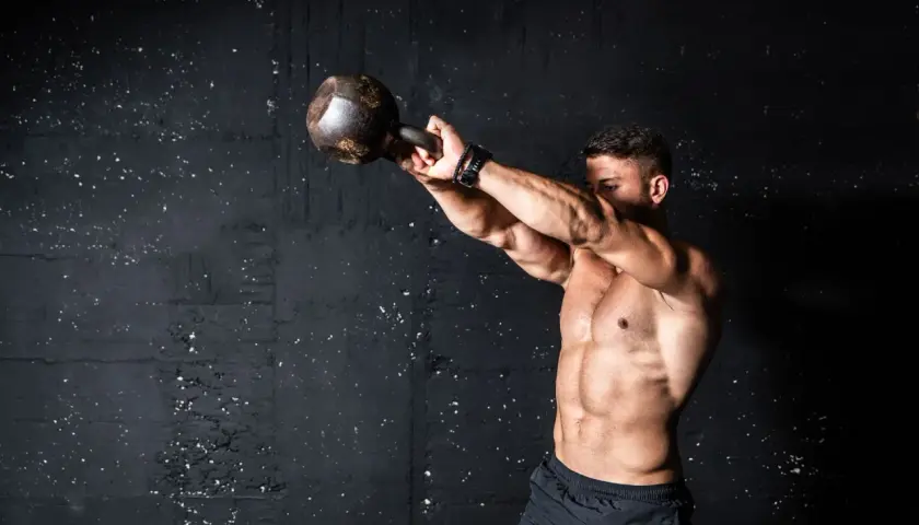 Mężczyzna ćwiczy z kettlebell. Intensywny trening, który pokazuje, co to znaczy wysiłek anaerobowy.