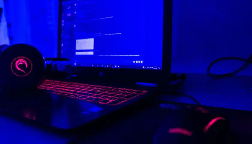 Gamingowy laptop z podświetlaną klawiaturą i słuchawkami, gotowy do tworzenia rankingu laptopów gamingowych.