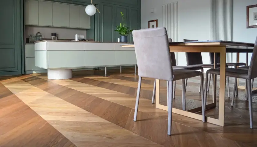 Un elegante soggiorno con cucina moderna e un **miglior parquet** a spina di pesce, che crea un gioco di luci e ombre.