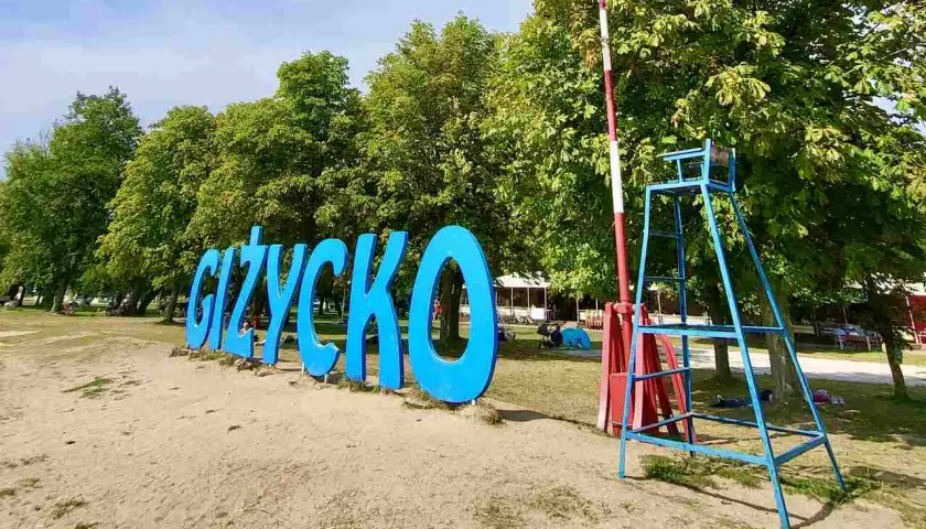 Napis GIŻYCKO na plaży, obok ratownicza wieża. Idealne miejsce na wakacje, mnóstwo giżycko atrakcje dla dzieci.