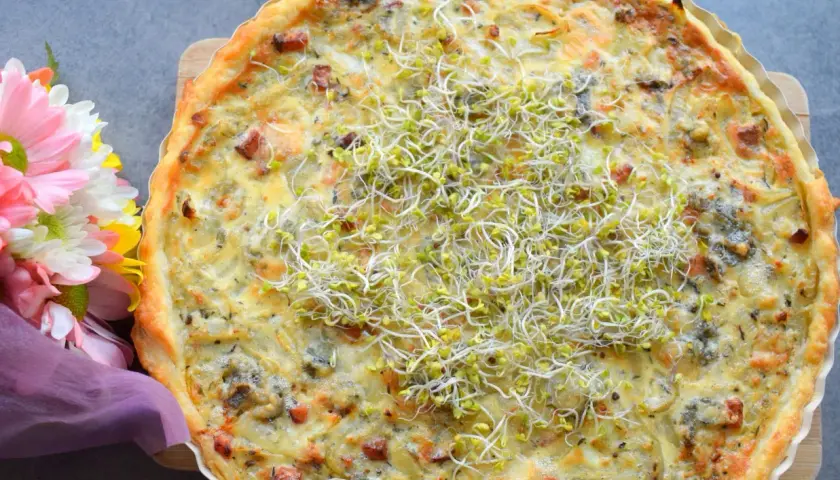 Pyszna tarta cebulowa z boczkiem, udekorowana kiełkami. Idealna na obiad lub kolację.