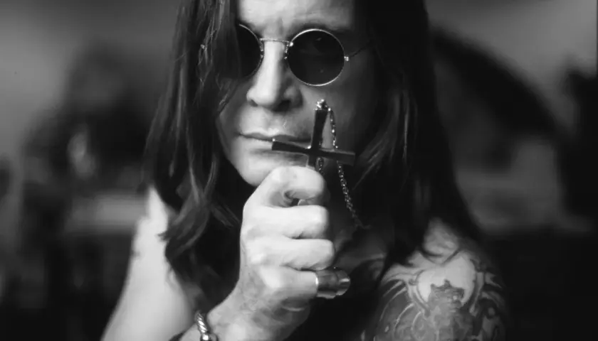 Ozzy Osbourne, ikona zespołu Black Sabbath, w okularach i z krzyżem w dłoni.