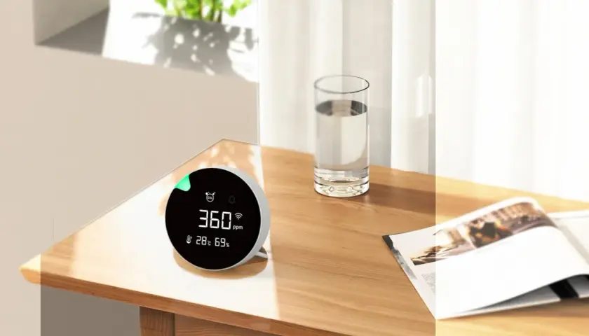 Monitor de calidad del aire muestra 360 ppm, indicando niveles de CO2 saludables en un ambiente hogareño.
