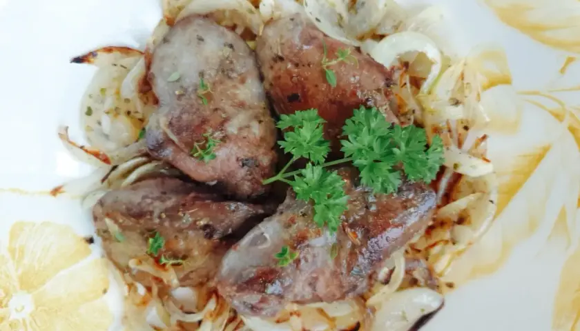 Smażona watrobka drobiowa z cebulką, udekorowana natką pietruszki i tymiankiem.