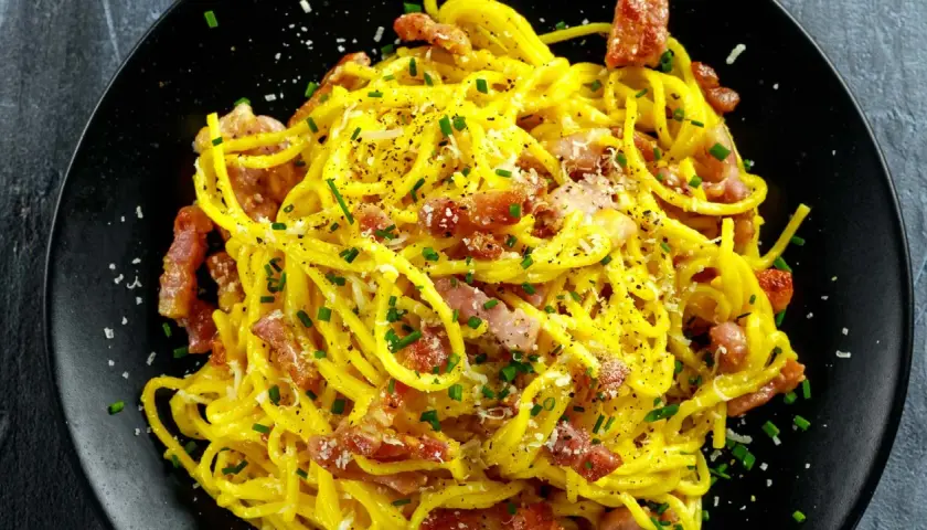 Spaghetti crémeux à la carbonara, garni de lard italien croustillant, de parmesan râpé et de ciboulette fraîche. Un délice !