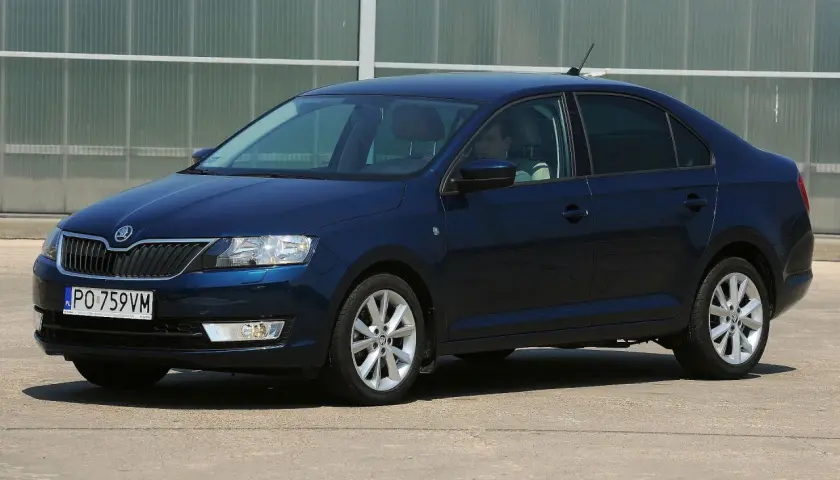 Ciemnoniebieska Skoda Rapid stoi na parkingu. Widoczny jest rozmiar opon, który idealnie pasuje do tego modelu.