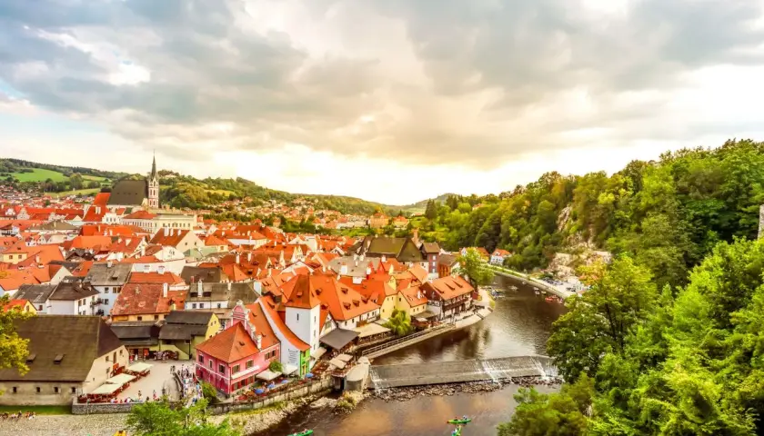 Malerische Stadt Český Krumlov, ein beliebtes Ausflugsziel in Tschechien, mit roten Dächern, Fluss und grünen Hügeln.