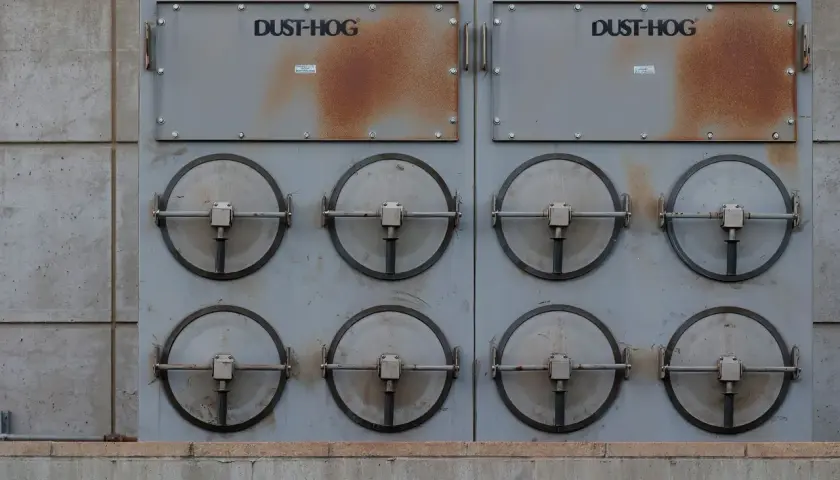 Dwa moduły przemysłowe DUST-HOG z ośmioma okrągłymi klapami, wykorzystujące zaawansowaną **technikę próżniową** do oczyszczania powietrza.