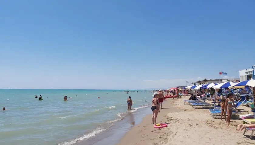 Giornata di sole al Metaponto Lido. Gente in acqua e sotto gli ombrelloni, bagnanti che si godono la spiaggia.