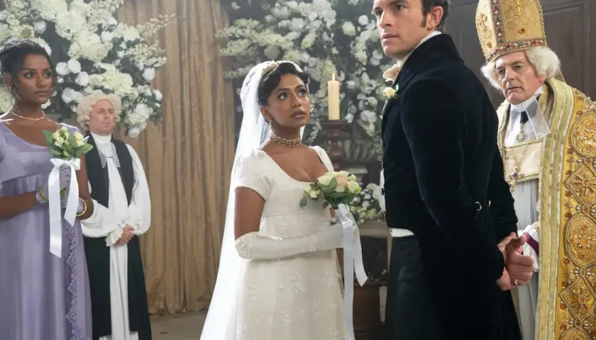 La mariée, le marié et le clergé se tiennent dans une église ornée de fleurs pour un mariage Bridgerton.