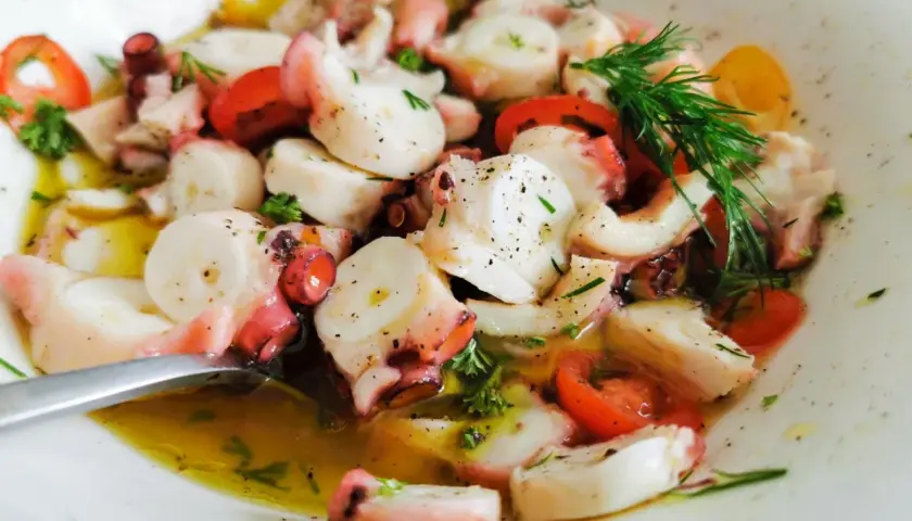 Ein köstlicher **pulpo salat original** mit zarten Oktopus-Stücken, Tomaten und frischen Kräutern in Olivenöl.