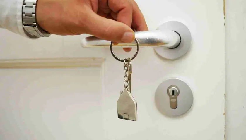 Main tenant ouvre la porte avec une clé en forme de maison. Les travaux ne sont pas finis, mais le paiement est attendu.