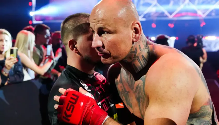 Artur Szpilka w czerwonej rękawicy KSW obejmuje przeciwnika.