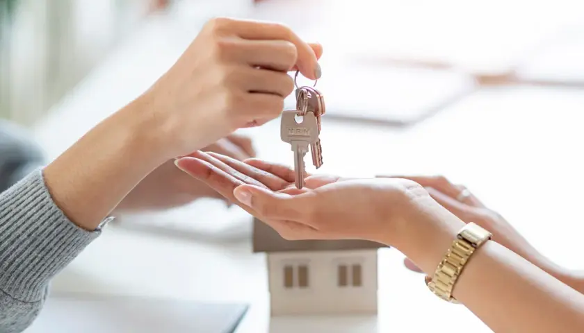 Manos intercambian llaves de una casa modelo. Un nuevo comienzo, que significa cru, se materializa en este momento.