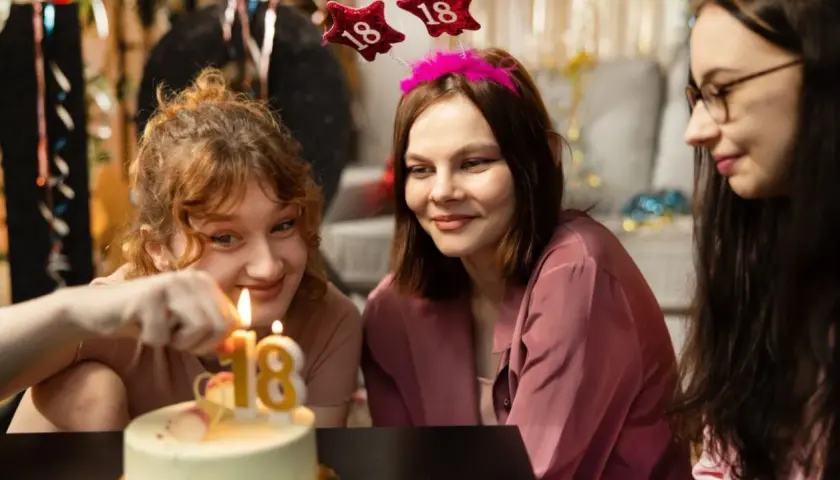 Drei junge Frauen feiern den 18. Geburtstag. Kerzen auf dem Kuchen leuchten, ein neues Kapitel beginnt, auch bezüglich Kindesunterhalt ab 18.