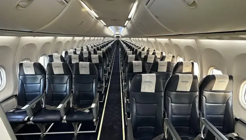 Wnętrze samolotu Enter Air. Ciemne fotele z zagłówkami z logo linii. Opinie forum o Enter Air często dotyczą właśnie takich widoków.