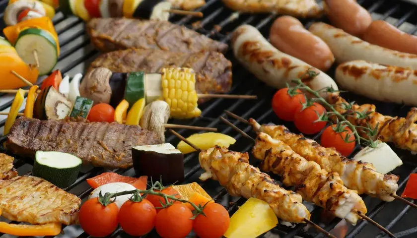 Brochettes de poulet, saucisses, steaks et légumes sur un barbecue. La température parfaite pour un barbecue savoureux.