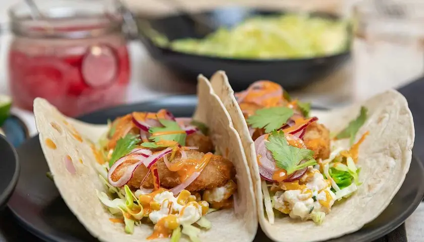 Två läckra fish tacos med krispig fisk, kål, rödlök och en krämig sås. Ett perfekt recept för en snabb och god middag.