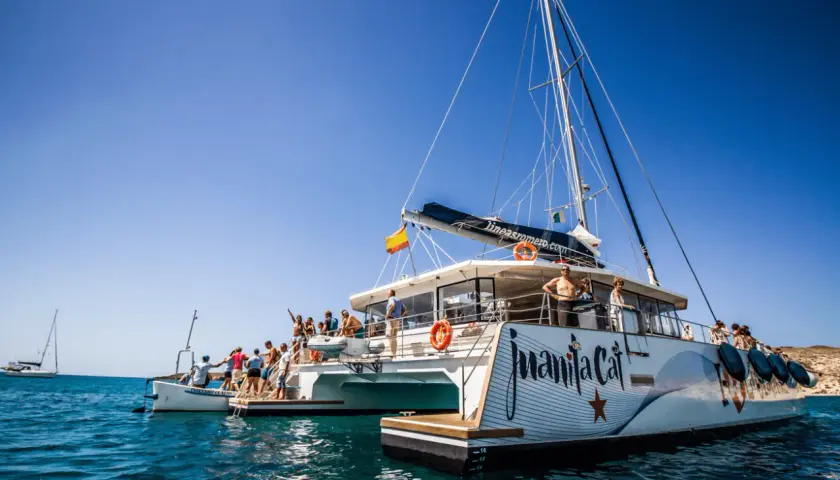 Catamarán "Juanita Cat" listo para el ferry Lanzarote La Graciosa. Turistas disfrutan del sol y el mar azul.
