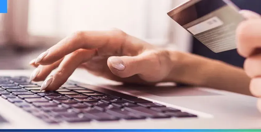 Dłonie wpisujące dane karty płatniczej na klawiaturze laptopa, ilustrujące najpopularniejsze metody płatności online.