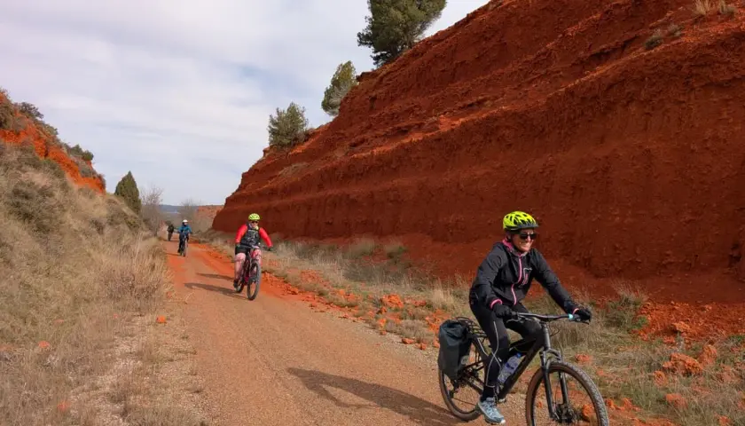 Ciclistas disfrutan de una **vía verde** con **ojos negros** en el paisaje rojizo.
