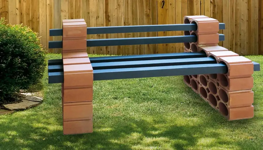 Eine rustikale Gartenbank, die man leicht selber bauen kann, mit Sitzflächen aus dunklen Balken und Stützen aus Ziegelsteinen.