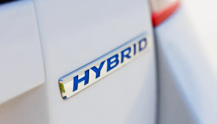 Niebieski napis HYBRID na białym samochodzie.