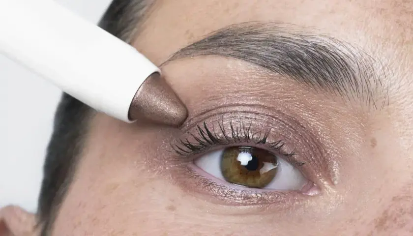 Application d'un fard à paupières bronze, couleur iris fleur, sur un œil.
