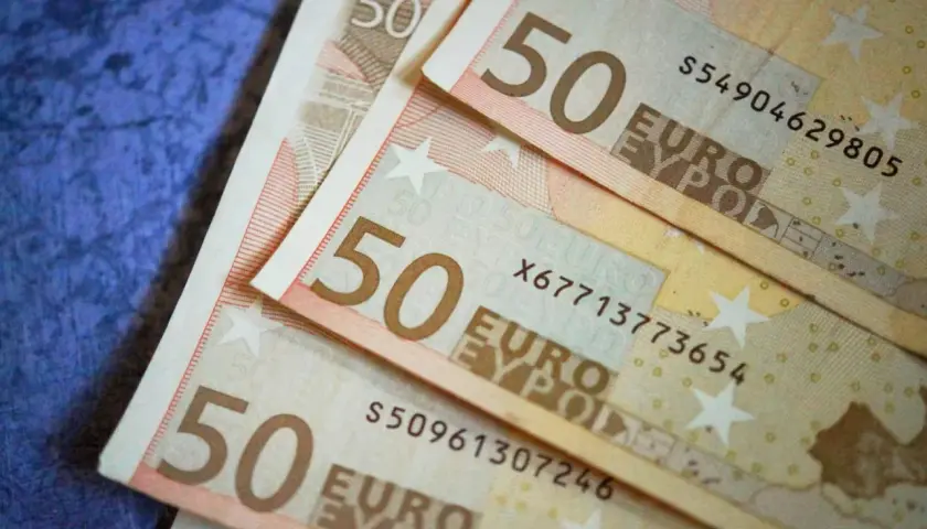 Trois billets de 50 euros sont empilés sur un fond bleu. Le coût de la vie est élevé, on est condamné aux dépens.