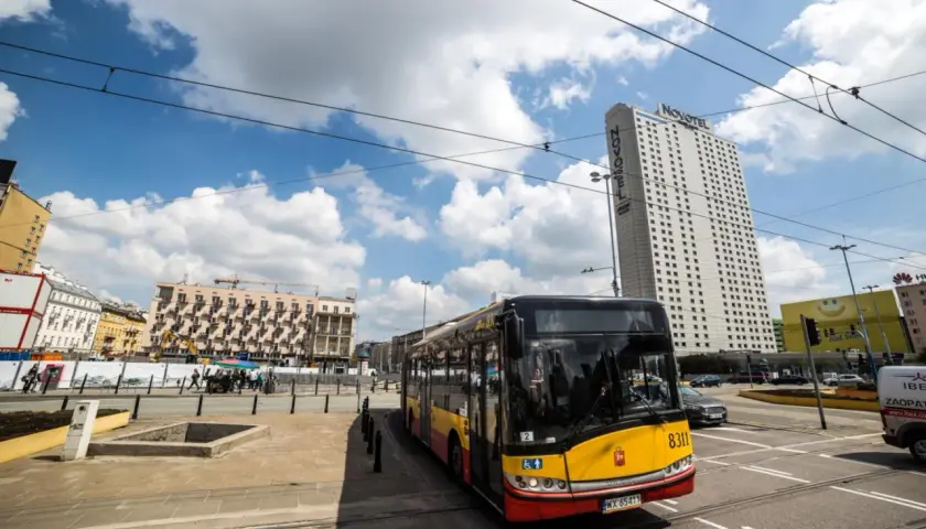 Autobus MZA Warszawa na tle wieżowca Novotel i budynków mieszkalnych.