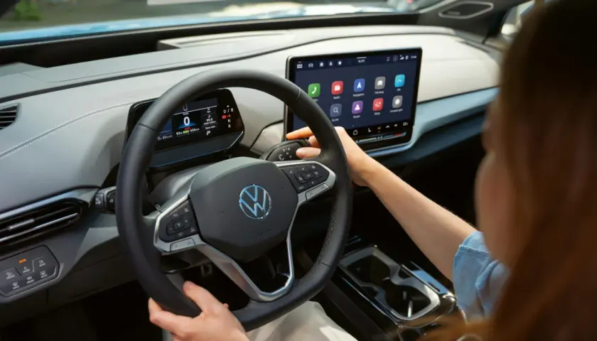 Interior de un coche eléctrico Volkswagen. Se ve el volante, la pantalla táctil central y la palanca de cambios. La dirección asistida progresiva se adapta a la velocidad.