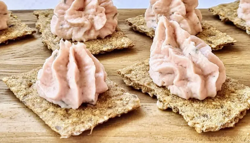 Petites bouchées de rillettes de jambon onctueuses sur des crackers croustillants, prêtes à être dégustées.