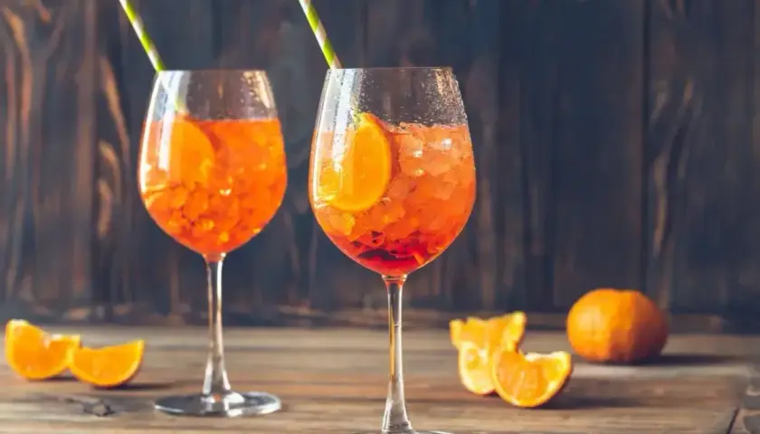 Dwa Aperol Spritz z pomarańczą i słomkami. Idealne proporcje na letnie popołudnie.