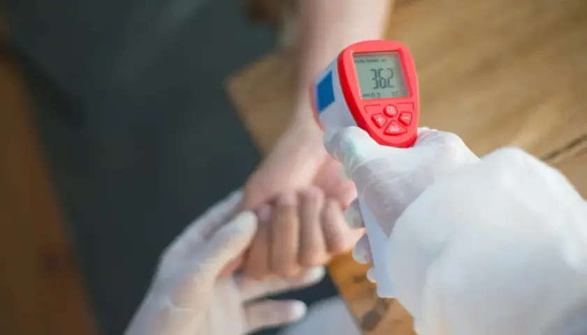 Rękawiczki i termometr bezdotykowy mierzą temperaturę, która może wskazywać na przewlekły stan podgorączkowy i zmęczenie.