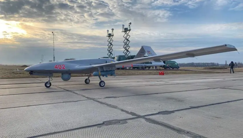 Szary dron Bayraktar TB-2 z numerem 402 na płycie lotniska, gotowy do akcji.