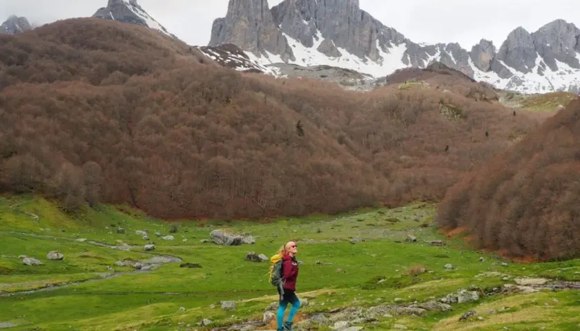 Senderista admira el majestuoso valle de Aspe, con picos nevados y bosques otoñales.