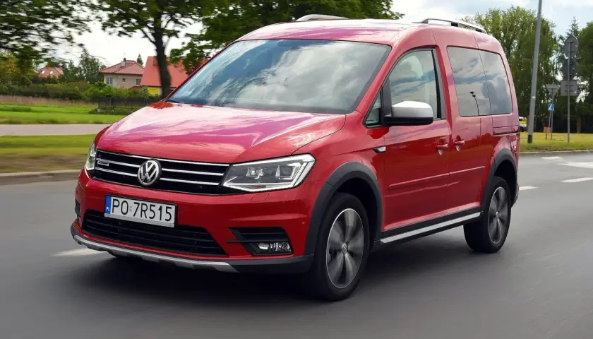 Czerwony Volkswagen Caddy 3 w ruchu, z widocznymi felgami i terenowym wyglądem.
