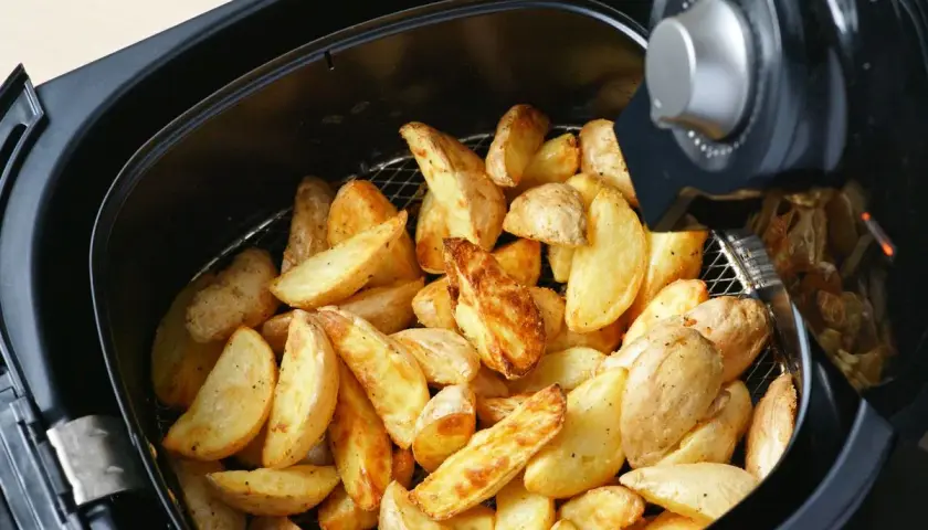 Patate a spicchi dorate e croccanti appena sfornate nella friggitrice ad aria.