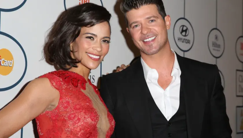 Paula Patton w czerwonej sukni i Robin Thicke na gali. Paula Patton znana z wielu filmów, uśmiecha się do aparatu.