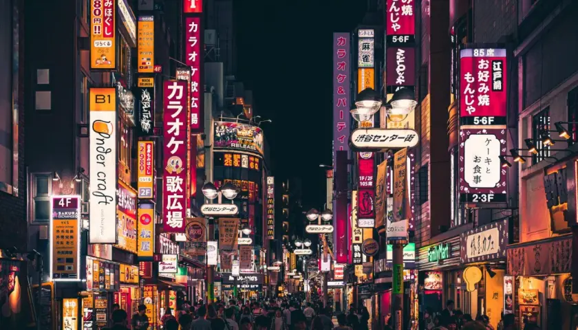 Nocna ulica Tokio z neonowymi szyldami i tłumem ludzi.