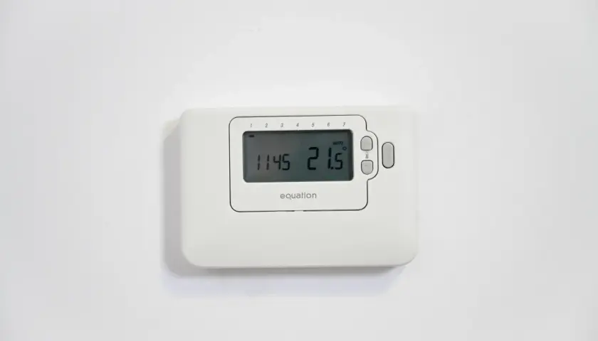Termostato Equation en pared blanca. Muestra la hora 11:45 y la temperatura 21.5°C. Ideal para cambiar el termostato de calefacción.